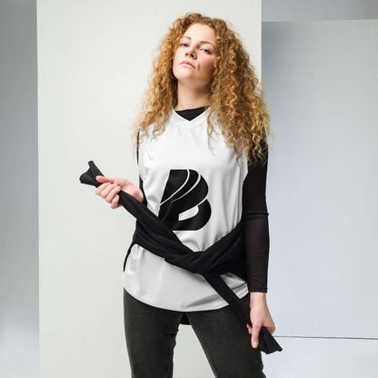 Woman wearing Recyceltes Unisex-Basketballtrikot N°0 styled as streetwear, holding black clothing item, standing confidently indoors.