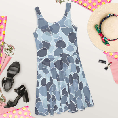 Skater-Kleid N°9 in blue patterned design with sleeveless cut and flared skirt, styled with black heels and beach accessories.