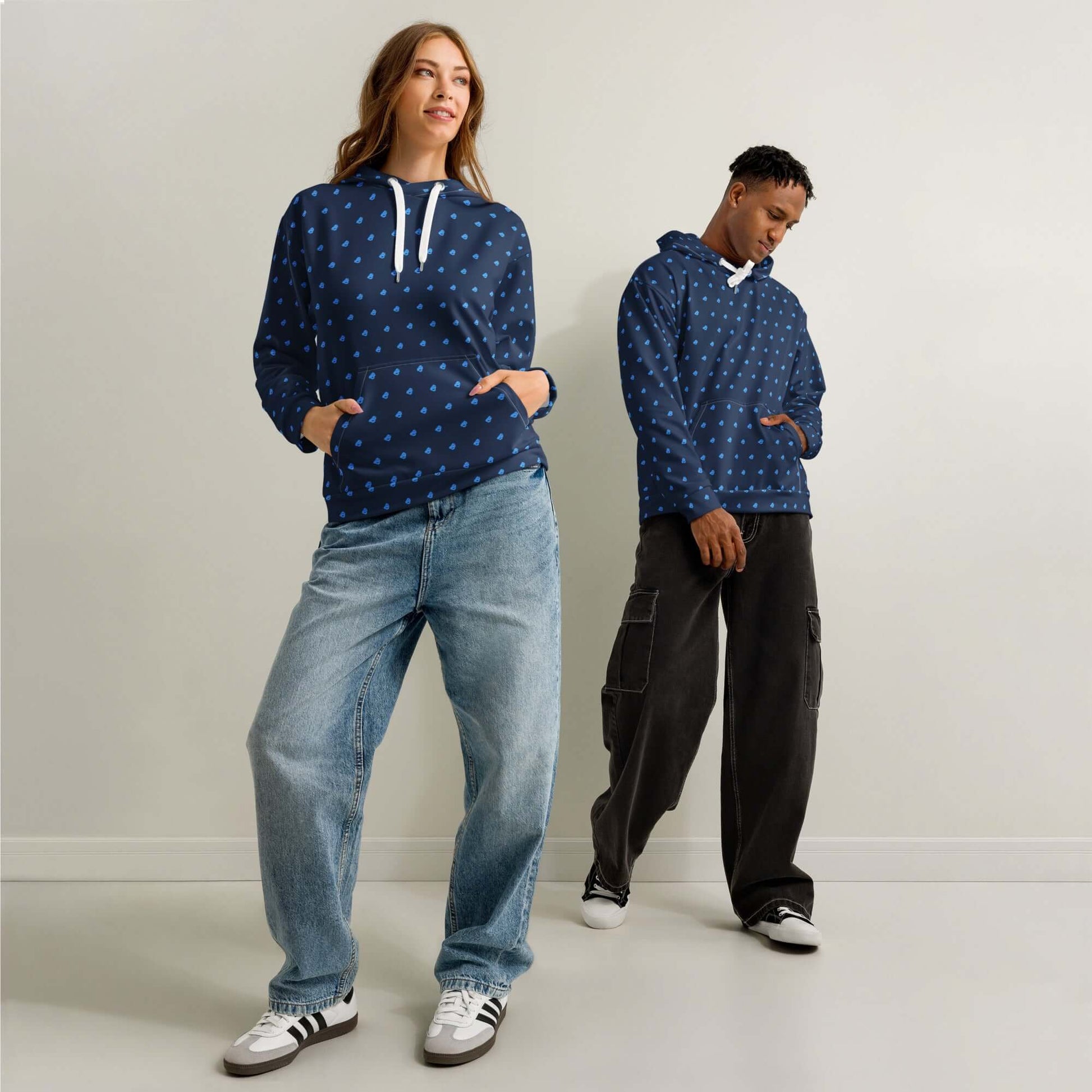 Two models wearing Unisex-Hoodie aus Baumwolle in a casual setting, displaying relaxed fit and allover print design.