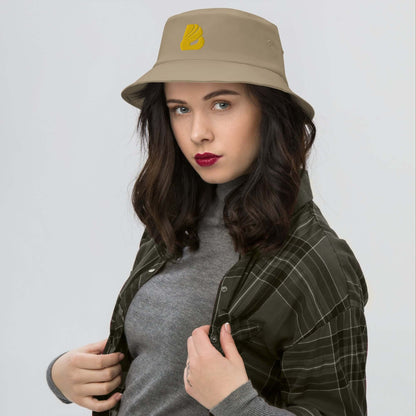 Woman wearing Old School-Fischerhut N°2, vintage-inspired bucket hat in beige with a yellow logo, stylish for 80s and 90s fashion revival.