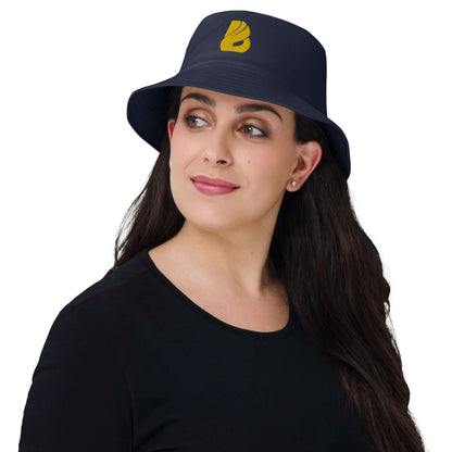 Woman wearing Old School-Fischerhut N°2, navy blue with yellow logo, showcasing vintage style and functionality.