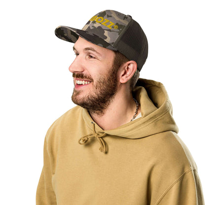 Man wearing Trucker-Hat im Camouflage-Look N°1 with beige hoodie, smiling, perfect for outdoor activities like fishing, camping, and hiking.