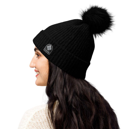 Woman wearing black Columbia Bommelmütze with faux fur pom-pom and soft microfleece lining, perfect for stylish winter warmth.