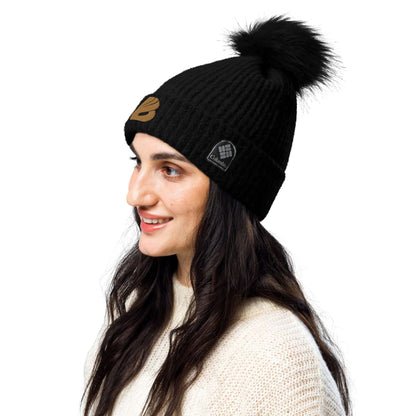 Woman wearing a black Columbia Bommelmütze with fluffy pompom, showcasing stylish winter headwear ideal for cold weather.