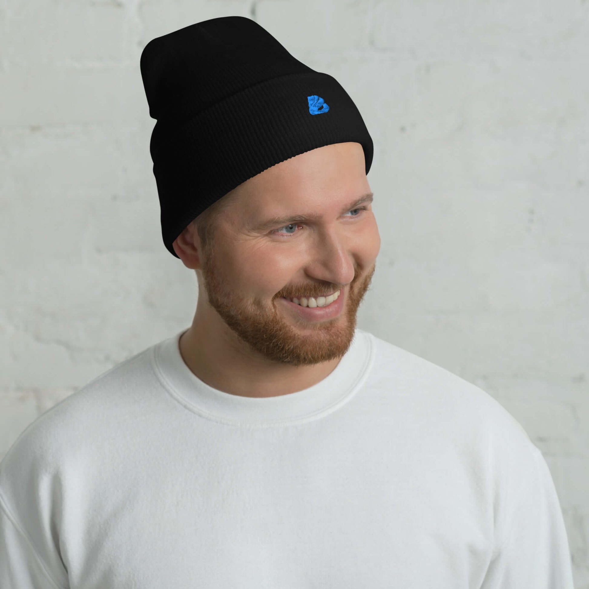 Umgeschlagene Beanie aus schwarzem Acryl, unisex, hypoallergen, zeigt Mann lächelnd. Kuschlige, warme Mütze für jeden Stil.