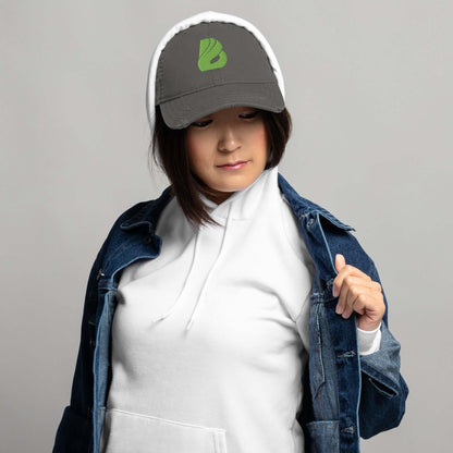 Frau trägt grauen Dad-Hat im Used-Look, kombiniert mit Jeansjacke und Kapuzenpullover, lässiger modischer Stil.