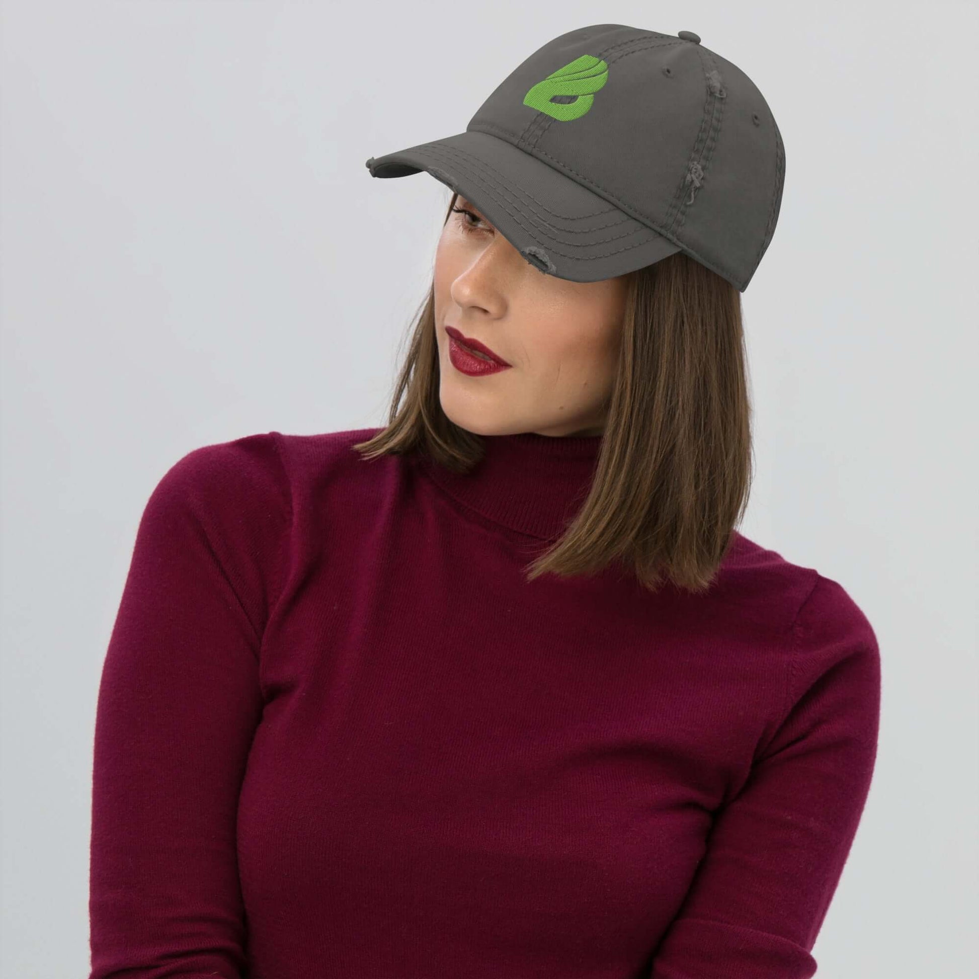 Frau trägt einen Dad-Hat im Used-Look in Grau, kombiniert mit einem weinroten Pullover, ideale Ergänzung für ein lässiges Outfit.