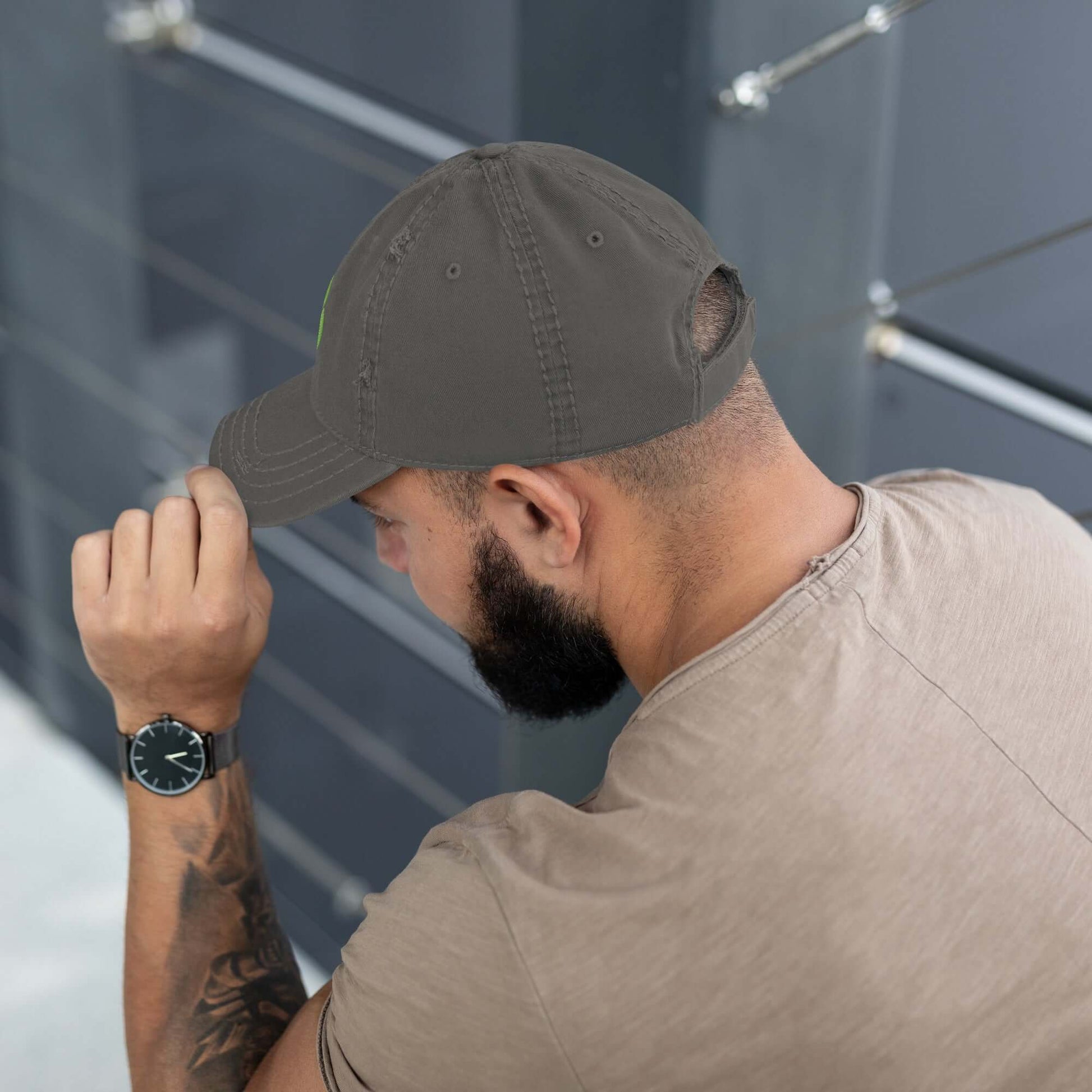 Man wearing a Dad-Hat im Used-Look in grey, turning head sideways, shows casual style with tattoo and wristwatch.