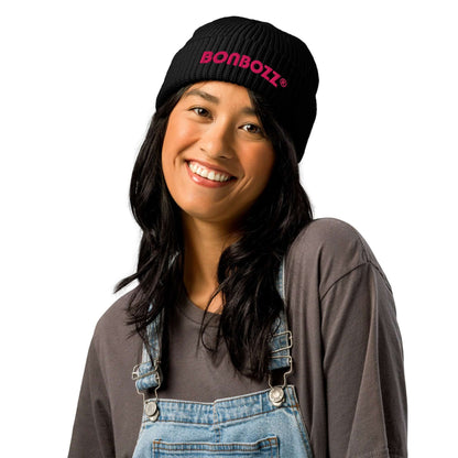 Woman wearing Fischermütze N°0 beanie in black with pink logo, stylish ribbed knit hat ideal for cold weather and versatile outfits.
