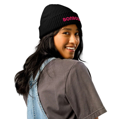 Woman wearing Fischermütze N°0, a trendy fisher-style beanie, in black with pink lettering, matching casual outfit.