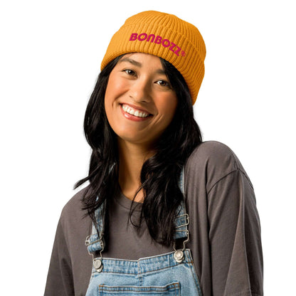 Smiling woman wearing a yellow ribbed beanie with 'Bonbozz' logo, styled casually for a trendy look.