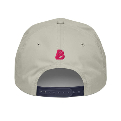 Back view of a beige Golfcap with a pink logo, adjustable snapback closure, and contrast band, made from 70% cotton, 30% nylon.