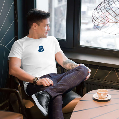 Mann trägt Herren-T-Shirt aus Premium-Baumwolle N°3, sitzt entspannt in Café, stilvolles legeres Outfit, Kaffeetasse auf Tisch. Luxuskleidung.