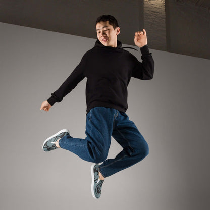 Person jumping in mid-air wearing a black hoodie and jeans, showcasing Herren-Canvas-Slipper N°2 sneakers for comfort and style.