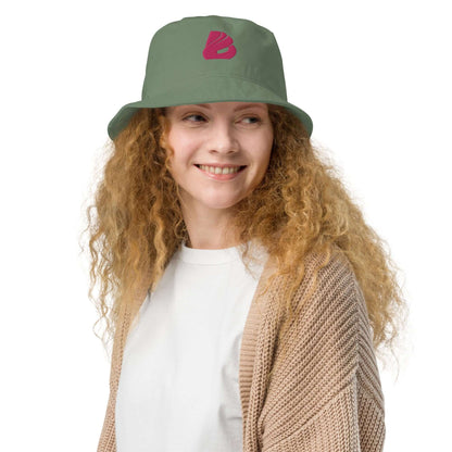Woman wearing Fischerhut aus Bio-Baumwoll-Twill N°0, stylish and eco-friendly hat in green with pink logo, comfortable and breathable.