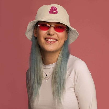 Person wearing Fischerhut aus Bio-Baumwoll-Twill N°1 with a stylish look, featuring a beige twill bucket hat and pink tinted sunglasses.