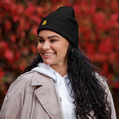 Woman wearing Gerippte Bio-Beanie outdoors, autumn background, stylish and eco-friendly fashion.