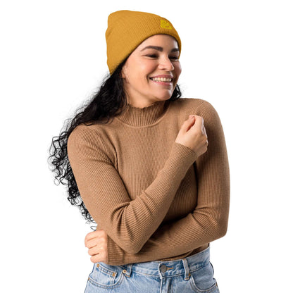 Smiling woman wearing Gerippte Bio-Beanie N°1 in mustard yellow, showcasing sustainable fashion made from 100% organic cotton.