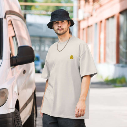 Man in street wearing Oversized T-Shirt mit verwaschenem Look N°1 and black hat, urban casual style, standing near a van.