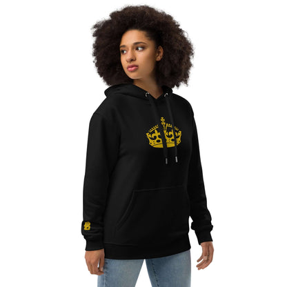 Person wearing Hochwertiger Öko Kapuzenpullover N°11 with yellow crown design on black hoodie