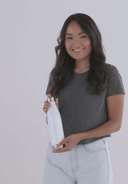 Woman holding Edelstahl Trinkflasche N°0, a stainless steel insulated bottle, showcasing design and portability.