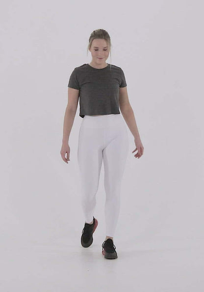 Woman wearing Yoga-Leggings N°3 in white, four-way stretch fabric with a high waistband, walking confidently in a fitness studio.