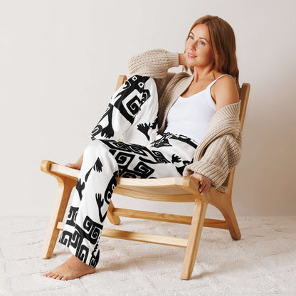 Frau trägt bequeme Pyjama-Hose für Damen in einem ruhigen Raum, stilvoll kombiniert mit einer Strickjacke auf einem Holzstuhl sitzend.