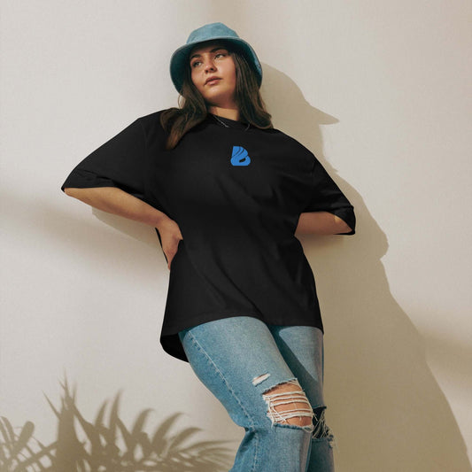 Schwarzes oversized T-Shirt in urbanem Look, kombiniert mit zerrissenen Jeans und blauen Bucket Hat.