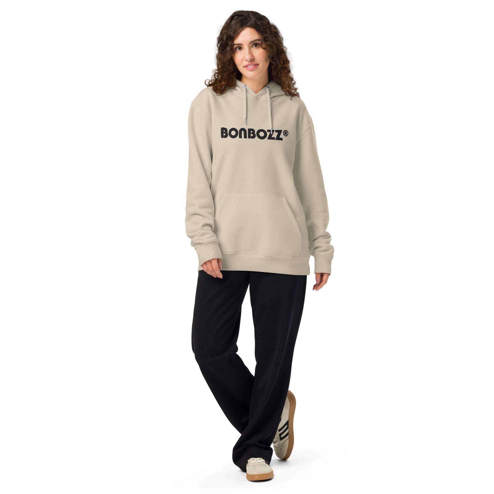Unisex Bio-Hoodie in beige, featuring BONBOZZ® logo, paired with black pants, showcasing streetwear style.