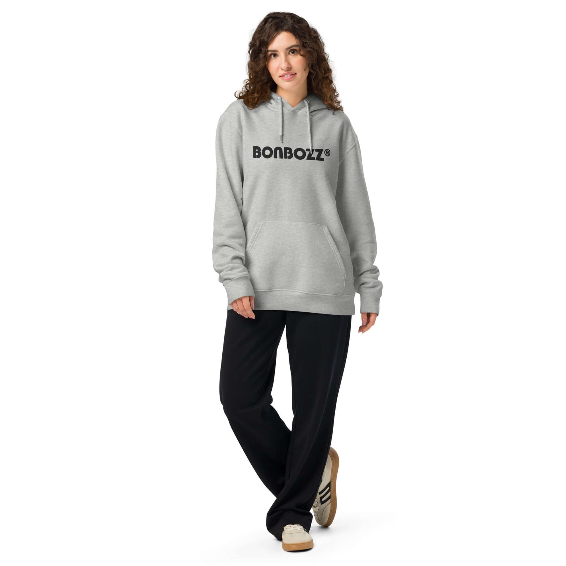 Unisex gray bio-hoodie with kangaroo pocket and logo, paired with black pants and casual shoes.