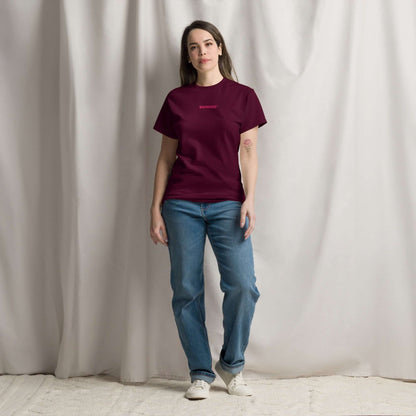 Woman wearing Klassisches Unisex T-Shirt N°0 in burgundy, styled with blue jeans against a neutral background.