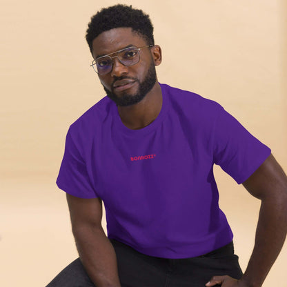 Man in a vibrant purple Klassisches Unisex T-Shirt N°0 made from 100% cotton, sitting in a modern style, perfect for streetwear outfits.