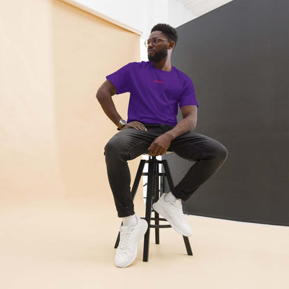 Klassisches Unisex T-Shirt N°0 in vivid color, perfect for layering with streetwear, shown on a model seated on a stool in a studio setting.