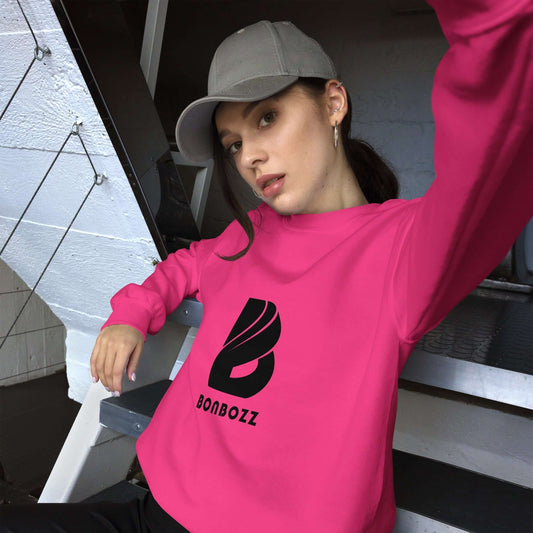 Woman wearing pink Unisex-Pullover with black logo, sitting casually on stairs, stylish and comfortable for colder months.
