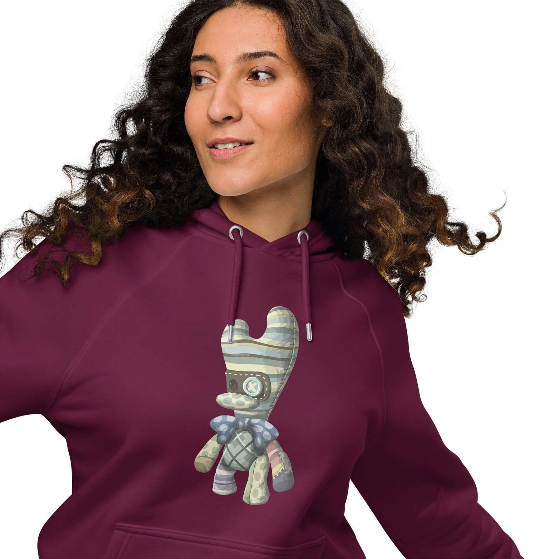 Unisex Bio-Raglan-Hoodie in burgundy with artistic design, worn by a person with long curly hair, showcasing stylish and comfortable fashion.