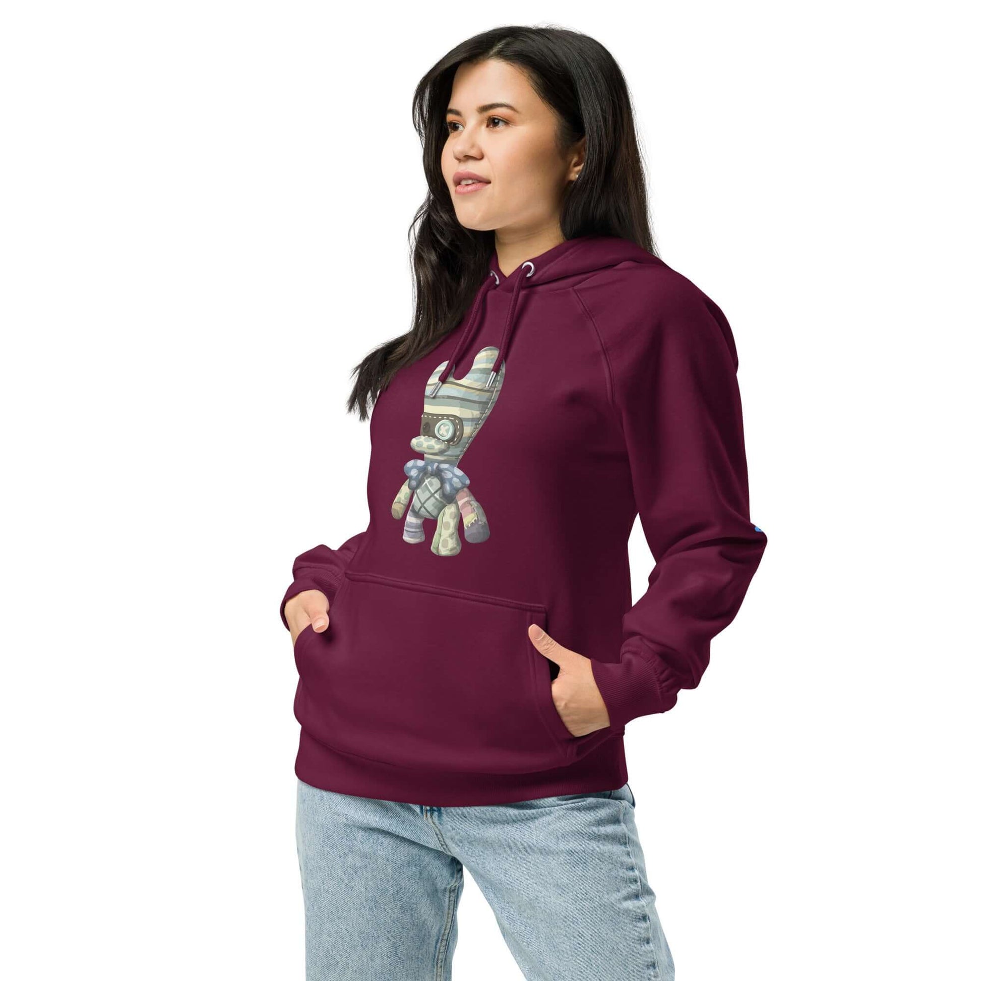 Model wearing Unisex Bio-Raglan-Hoodie in burgundy with a stylish graphic design, paired with casual jeans.