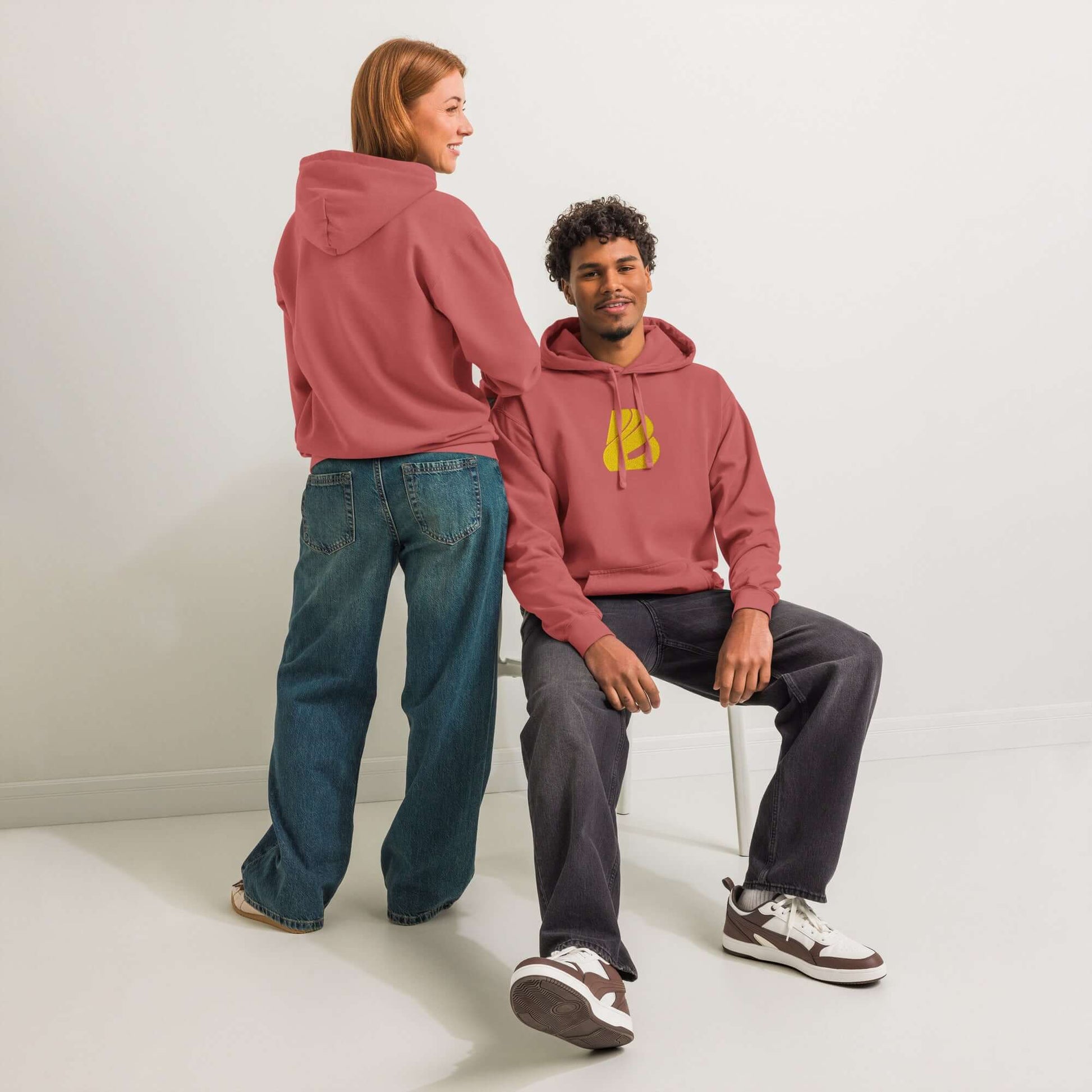 Man and woman wearing Textilgefärbter Unisex-Hoodie in casual setting, showcasing soft cotton blend and relaxed fit.