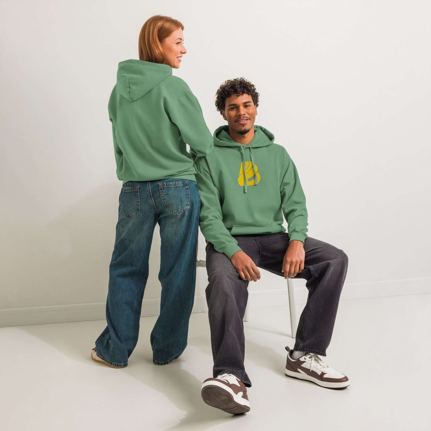 Textilgefärbter Unisex-Hoodie in Grün, getragen von zwei Personen in entspannter Pose, ideal für Komfort im Alltag.