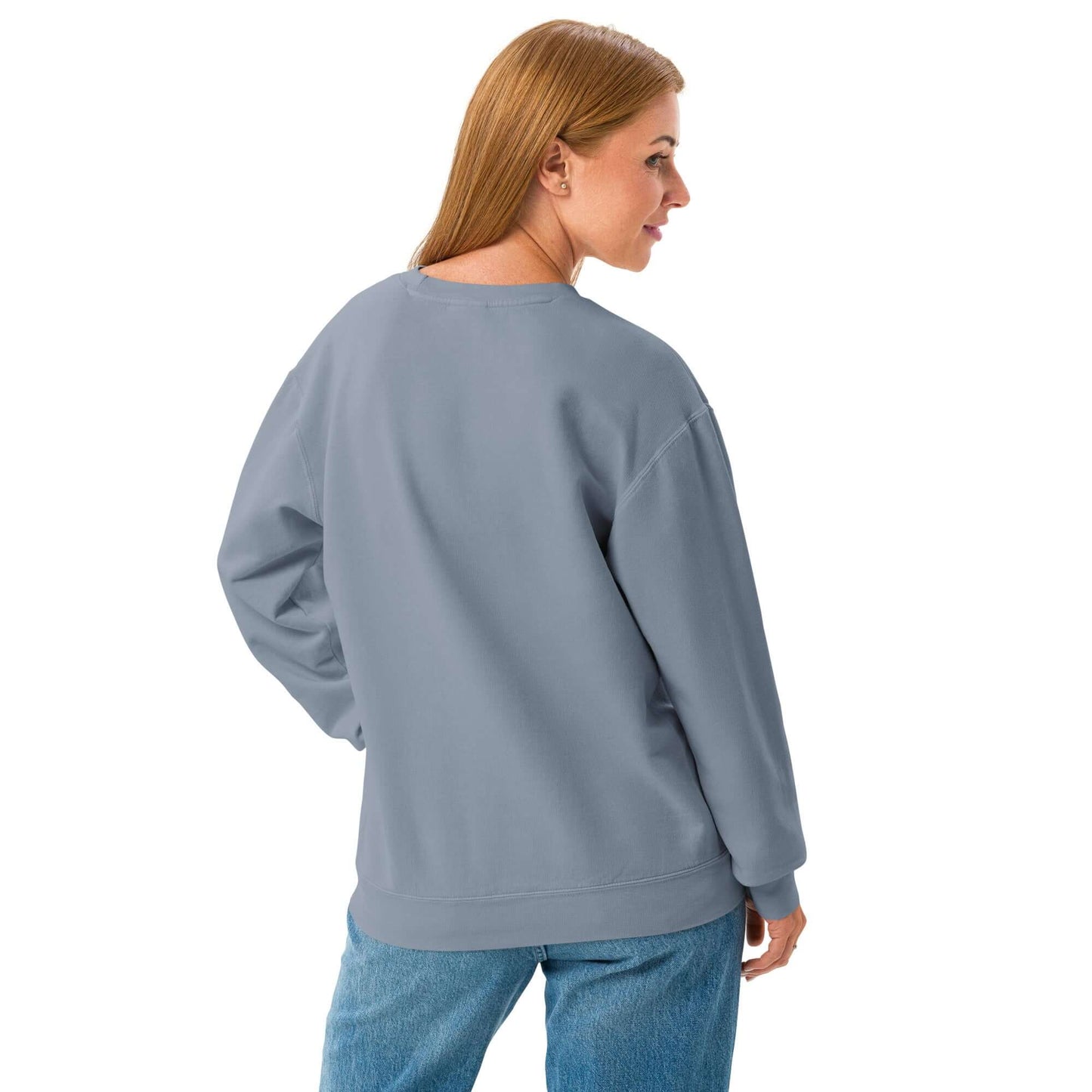 Rückansicht des leichten textilgefärbten Unisex-Fleece-Pullovers mit Rundhalsausschnitt in Blau, getragen von einer Person über blauer Jeans.