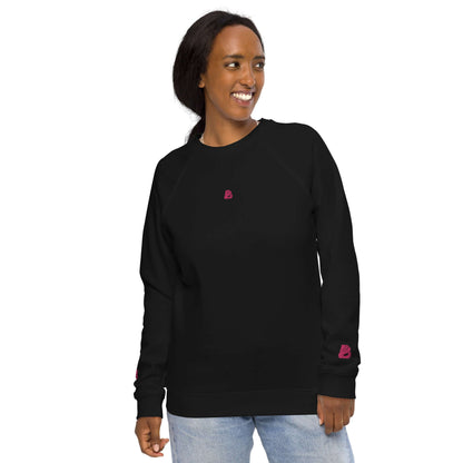 Woman wearing Unisex Bio-Raglan-Pullover N°3, black with pink accents, smiling in casual attire.
