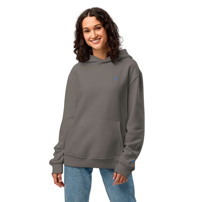 Woman wearing Schwerer Oversized Hoodie in grey, showcasing its soft fleece and spacious fit, ideal for lounging. Perfect blend of comfort and style.