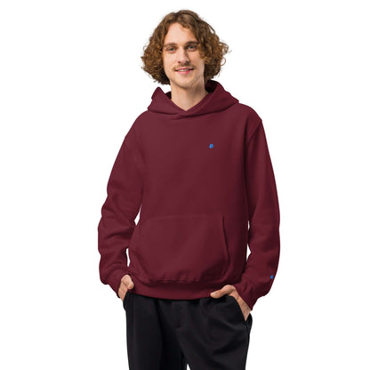 Man wearing a burgundy Schwerer Oversized Hoodie with hands in pockets, showcasing thick, soft fabric and cozy fit.