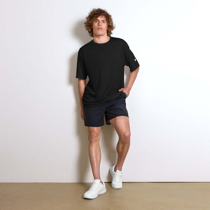 Man wearing Unisex Performance T-Shirt mit Rundhalsausschnitt N°0 in black, paired with shorts and white sneakers, ideal for sports and fitness.