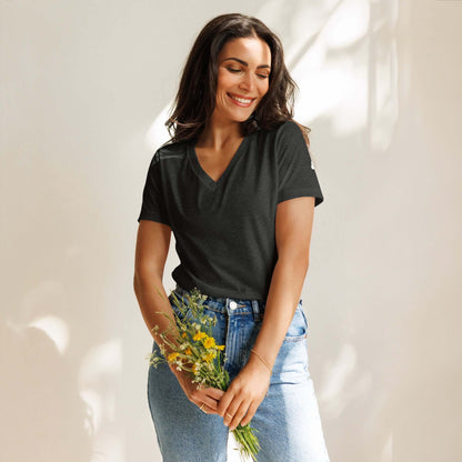 Woman wearing Lockeres Damen T-Shirt mit V-Ausschnitt N°1, holding flowers, standing against soft light background.