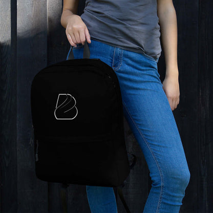 Person holding a black Rucksack N°2 against a dark wooden background, stylish and practical for daily use or sports activities.