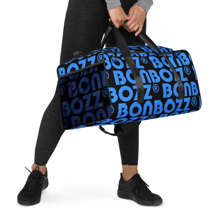 Person carrying Weekender N°25 in blue with black BOZZ lettering, adjustable shoulder straps, ideal for travel and fitness.