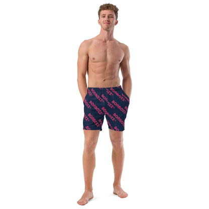 Model wearing Herren-Badehosen N°9, quick-drying and breathable with multiple pockets and anti-chafe lining, in navy with red text pattern.