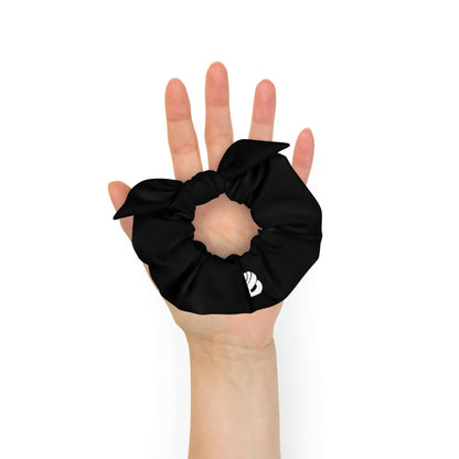 Black Scrunchie N°2 held in hand, made from sustainable materials; soft, stretchy fabric for stylish hair support.