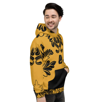 Person wearing Unisex-Kapuzenpullover N°18 with vibrant black floral print on mustard fabric, side view.