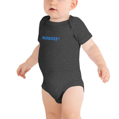 Baby wearing Kurzärmliger Baby-Einteiler N°0 in dark grey with blue print, made of 100% cotton, featuring comfortable snap closures.